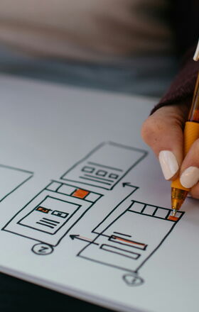 Eine Person zeichnet den groben Aufbau einer Website auf einem Blatt Papier.