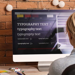 Foto einer Frau welche auf einen Computer Bildschirm schaut, auf diesem Bildschirm sind ist eine Farbpalette zu sehen sowie Text in verschiedenen aufeinander abgestimmten Größen zu sehen.
